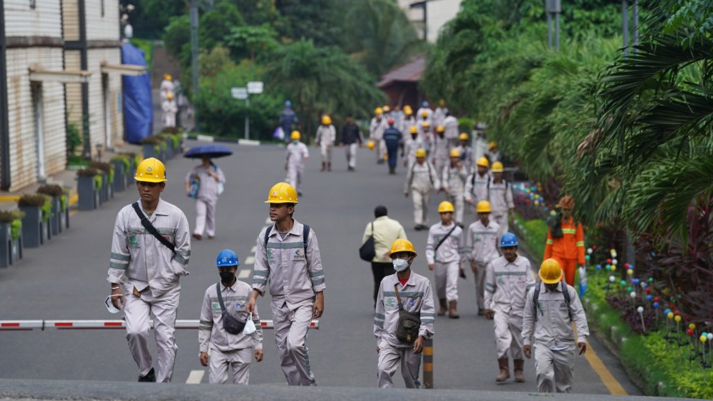 Ribuan karyawan di kawasan IMIP mengenakan seragam alat pelindung diri lengkap berjalan sepulang jam kerja. Mobilitas para pekerja menjadi pemandangan harian dari ritme industri yang terus bergulir.